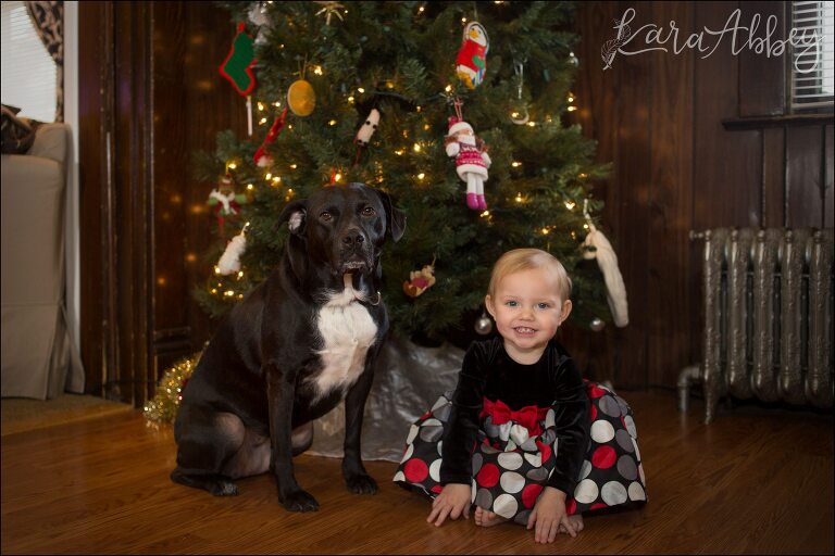 A toddler and her dog sitting in front of the Christmas Tree, anxiously awaiting Christmas morning!